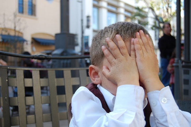 Young boy covering face with hands in social embarrassment